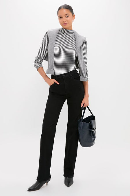 Young woman exudes effortless style in the classic Nighty Night The Kick It ensemble, featuring high-end striped top, sleek black jeans, and chic accessories, embodying fun sophistication.