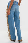 Model wearing Folk Star The Fringe Half-Pipe Button Sneak jeans with classic straight-leg cut and fun tan-suede fringe, paired effortlessly with high-end brown boots.
