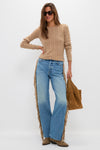 Woman models Folk Star The Fringe Half-Pipe Button Sneak with an effortlessly cool, classic boho look, featuring fringed jeans and matching tan suede accessories, embodying fun, high-end style.