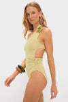 Model wearing the classic Leek Green Ecos One Piece, an effortless swimsuit featuring a one-shoulder design, floral detail, and stylish cut-out, paired with chunky bangles.