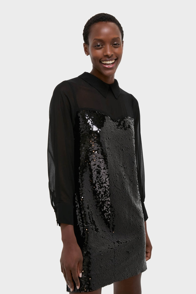 Smiling person wearing the Black Sequin Josie Dress: a classic, high-end piece with a sheer, long-sleeved top and an effortlessly fun, sequin-embellished body.