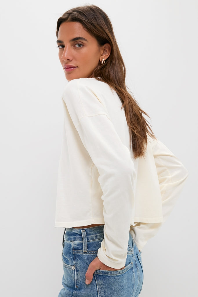Woman in Martini Soup Crop Long Sleeve Tee by ASKK NY, paired with medium-wash jeans, embodying a classic, effortless style.