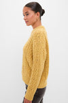 Young woman in profile wearing the Sunflower Madelyn Sweater, a classic, chunky mustard cable-knit with a relaxed fit, embodying effortless style and fun sophistication.