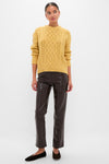 Woman wearing Sunflower Madelyn Sweater, a classic mustard cable-knit with relaxed fit, paired with dark leather pants and black flats. Effortless, high-end look.