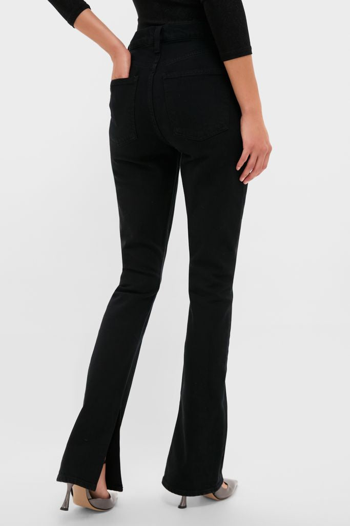 Model showcasing Immersion Ingram Split Skinny jeans: classic high-waisted black denim with a slim thigh fit, flared legs, and back slits, styled effortlessly fun with heeled shoes.