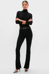 Woman wearing Immersion Ingram Split Skinny jeans with a classic black turtleneck, metallic heels, and a slim belt, embodying an effortless, high-end, and fun style.