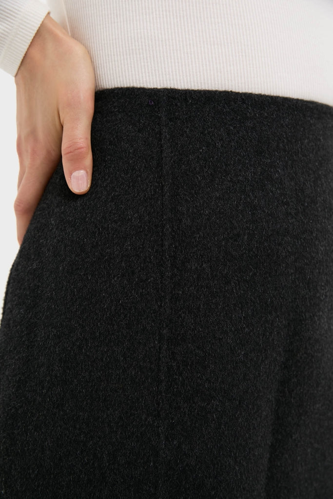 Black Naomi Mini Skirt with A-line silhouette, effortlessly tucked into a white ribbed top, exudes classic, high-end style for any fun occasion.
