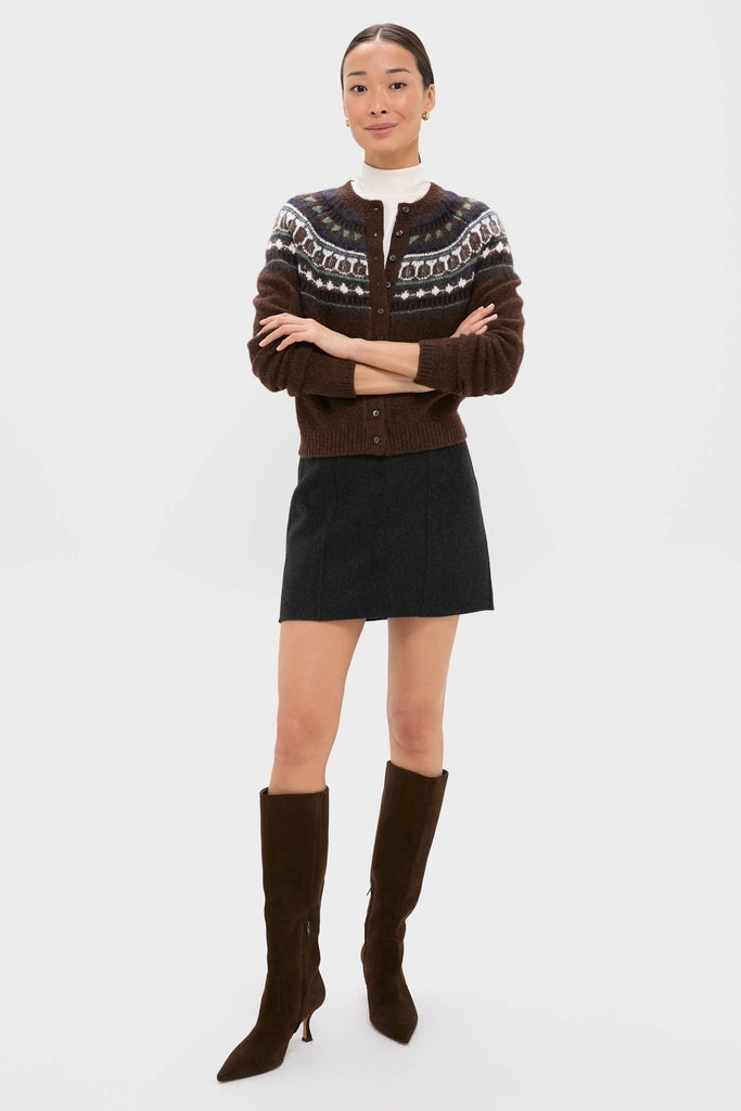 Woman models the classic Black Naomi Mini Skirt, styled with an effortless fair-isle cardigan, turtleneck, and high-end suede boots for a fun, chic winter look.