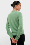 Young person in a Meadow Green Cashmere Covered Button Quinn Cardigan and black pants, exuding a classic, effortless style with high-end appeal.