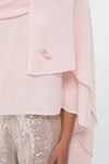 Ballet Slipper Cashmere Blanket Scarf draped effortlessly over shoulders, featuring a tonal-pink monogram, paired with fun, high-end light-gold sequined trousers for a classic look.