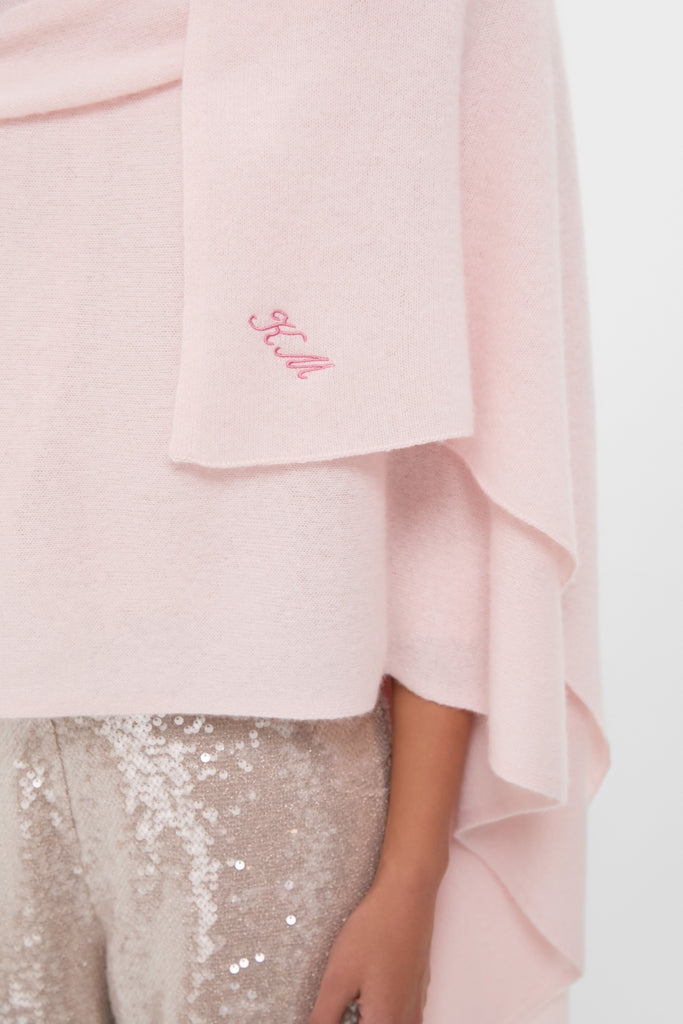 Ballet Slipper Cashmere Blanket Scarf draped effortlessly over shoulders, featuring a tonal-pink monogram, paired with fun, high-end light-gold sequined trousers for a classic look.