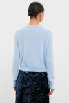 Back view of a woman in an Ice Blue Cashmere Riley Cardigan, showcasing its classic, effortless style paired with a high-end, fun navy sequin skirt.