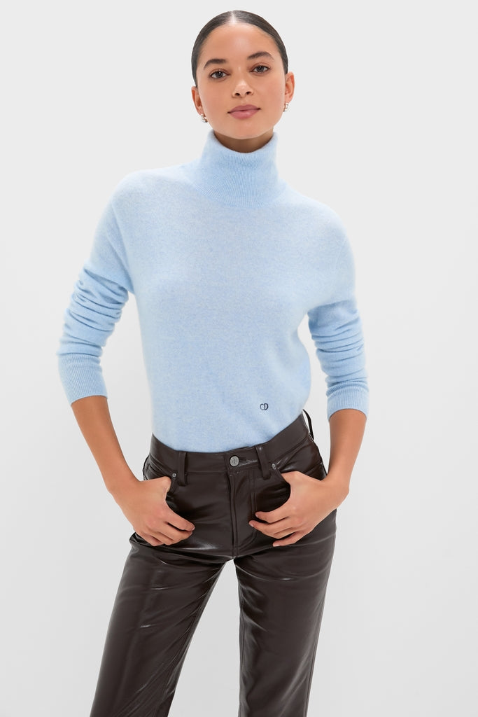 Model wearing a classic Ice Blue Cashmere Turtleneck Sweater, effortlessly styled with high-waisted black leather pants, embodying a fun and high-end Tuckernuck aesthetic.