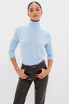 Model wearing a classic Ice Blue Cashmere Turtleneck Sweater, effortlessly styled with high-waisted black leather pants, embodying a fun and high-end Tuckernuck aesthetic.