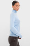 Young woman models the Ice Blue Cashmere Turtleneck Sweater, showcasing a classic, effortless look paired with dark, slim-fit pants for a high-end, fun fashion statement.