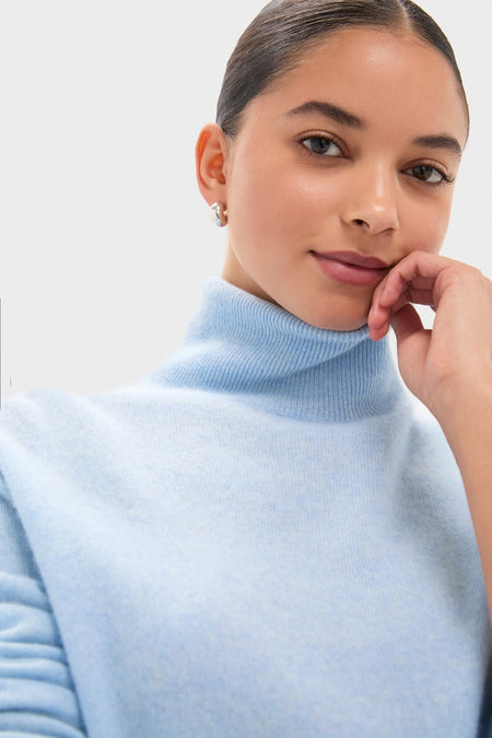 Young adult wearing an Ice Blue Cashmere Turtleneck Sweater, showcasing its classic, effortless elegance. The sweater's soft texture complements the serene, high-end style, embodying fun sophistication.