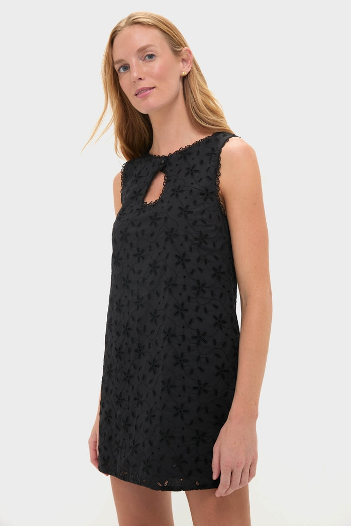 Model wears the Black Salma Mini Dress, a classic, effortless, high-end piece with eyelet floral patterns and lace-trimmed keyhole, embodying fun sophistication.