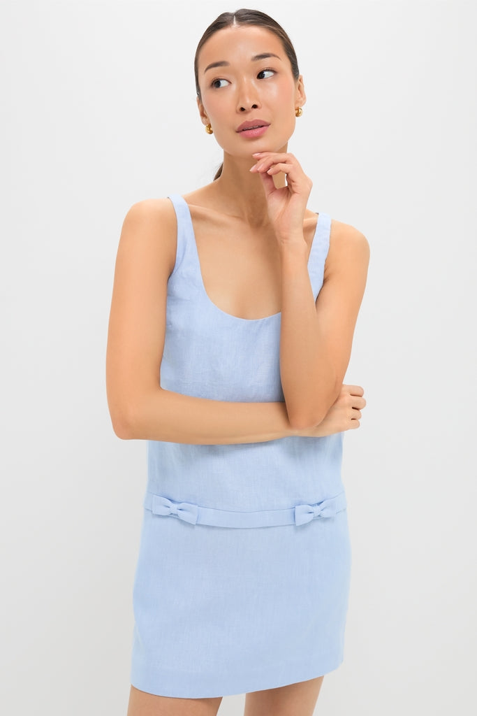 Young woman wearing the Blue Harper Mini Dress, a classic and effortless high-end piece with a scoop neck, self-fabric belt, and bow accents, exuding fun sophistication.