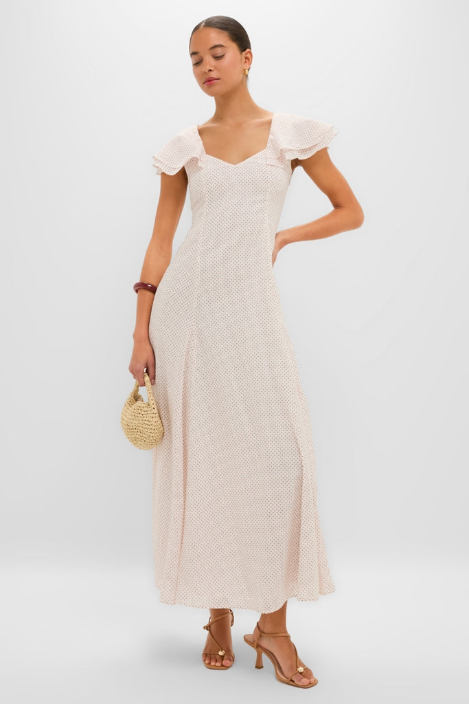 Woman in classic Cream and Red Polka Dot Marlowe Flutter Dress, effortlessly styled with fun tan sandals, a woven handbag, and high-end gold hoop earrings.
