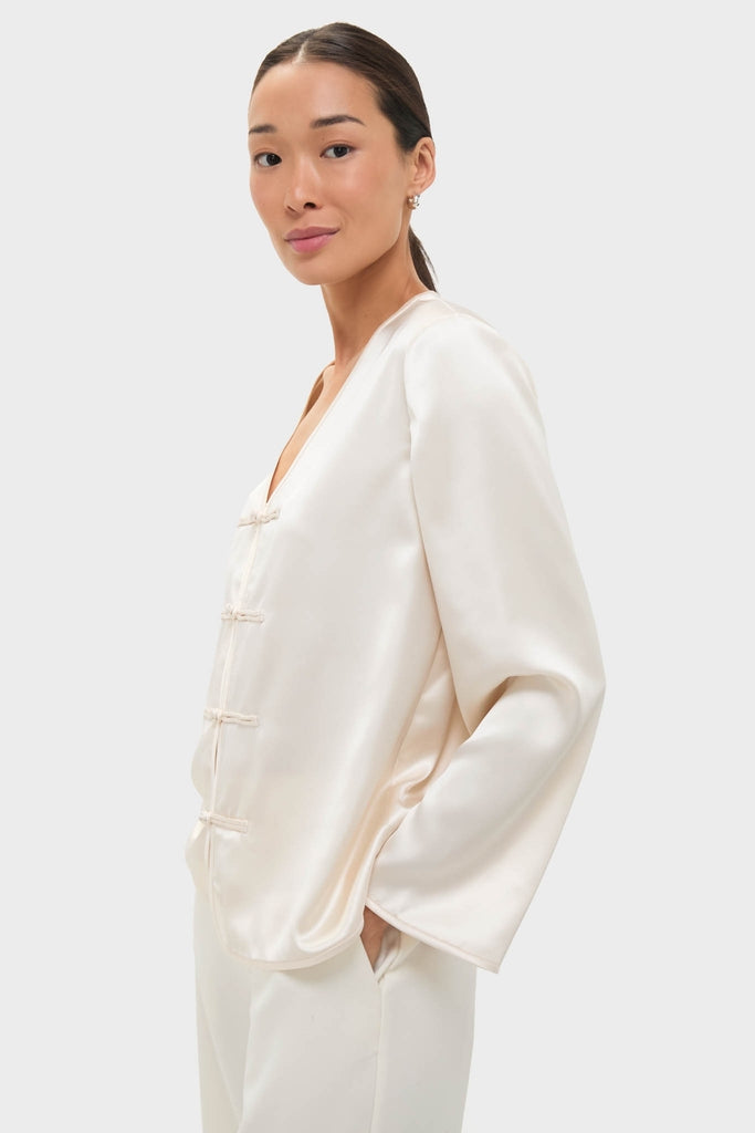 Woman wearing the classic Cream Satin Tatiana Blouse with chic frog closures, embodying an effortless, high-end style perfect for fun, elevated occasions.