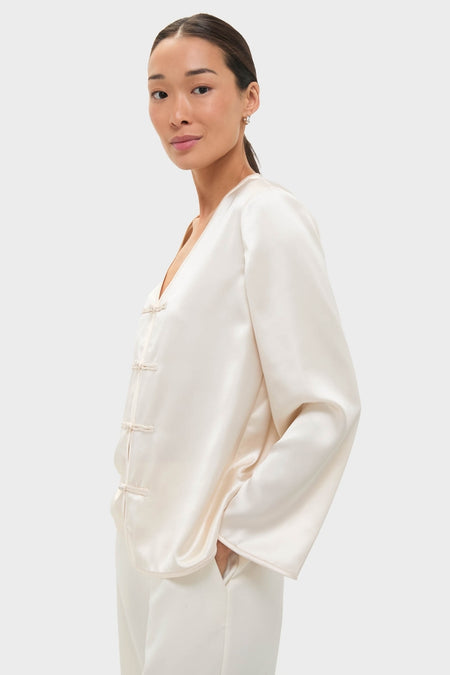 Woman wearing the classic Cream Satin Tatiana Blouse with chic frog closures, embodying an effortless, high-end style perfect for fun, elevated occasions.