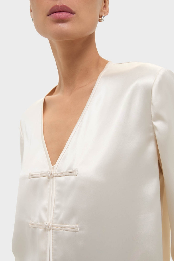 Cream Satin Tatiana Blouse with a classic V-neckline and chic frog closures, effortlessly blending fun and high-end style for day to night chic.