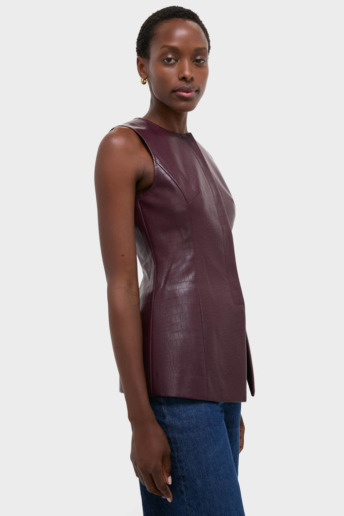 Woman wearing classic, high-end Plum Stamped Faux Leather Duke Top with croc-embossed texture, paired effortlessly with blue jeans and gold hoop earrings for a chic, fun look.