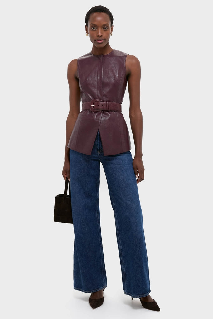 Model wearing the Plum Stamped Faux Leather Duke Top, a sleeveless, high-end burgundy piece with a crocodile texture, paired effortlessly with classic wide-leg jeans.