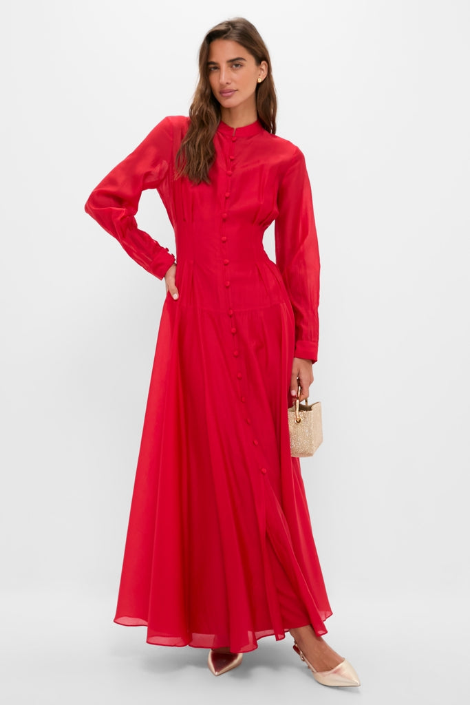 Woman wearing the classic Red Organza Marbella Dress with blouson sleeves and pintucks, holding a glittery gold handbag, embodying effortless, high-end style for fun occasions.