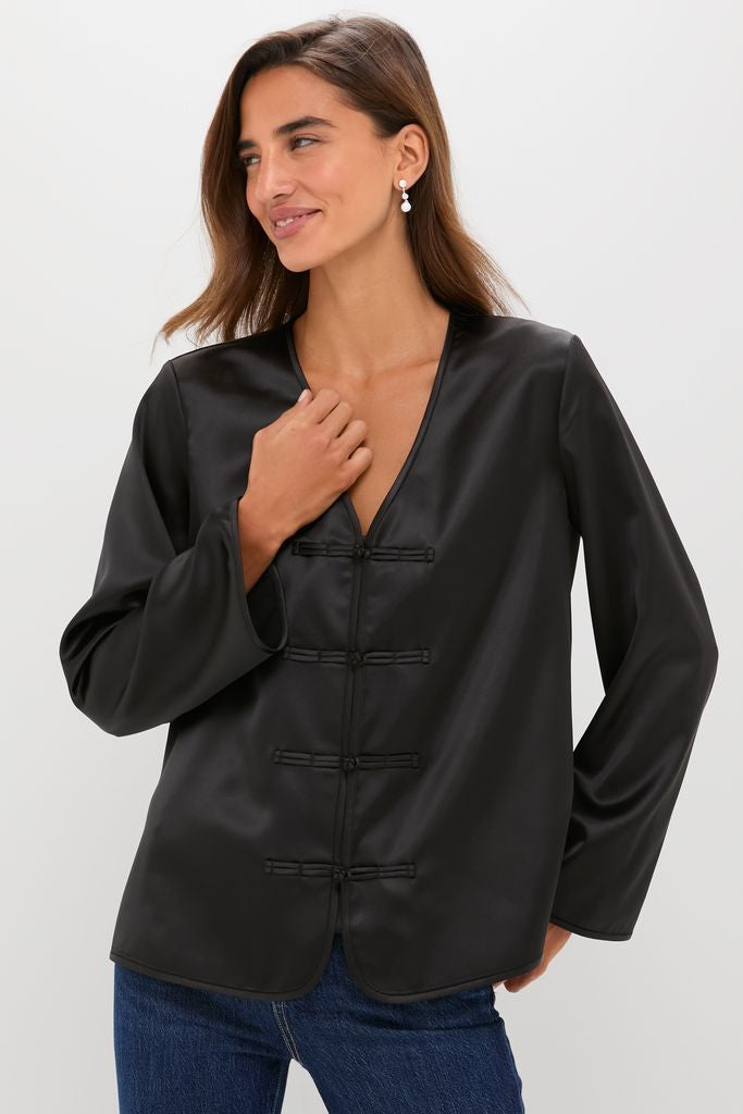 Black Satin Tatiana Blouse with classic frog closures, worn effortlessly by a smiling model. Ideal for fun, high-end occasions.