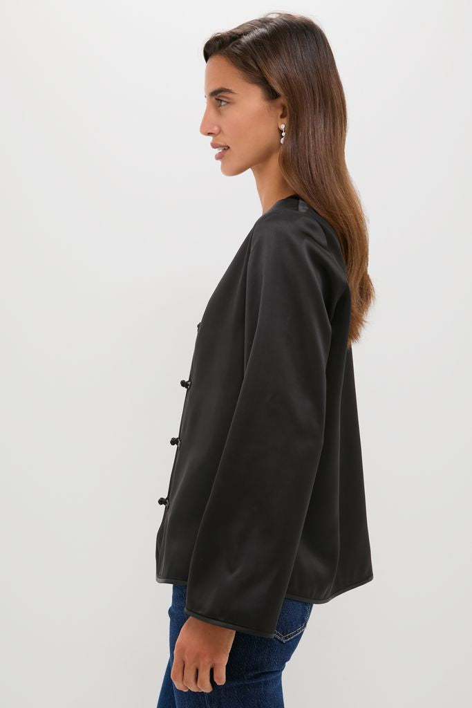Black Satin Tatiana Blouse with classic frog closures, V-neckline, and relaxed fit. Effortlessly chic and fun, perfect for high-end occasions. Paired with denim for an easy, confident look.
