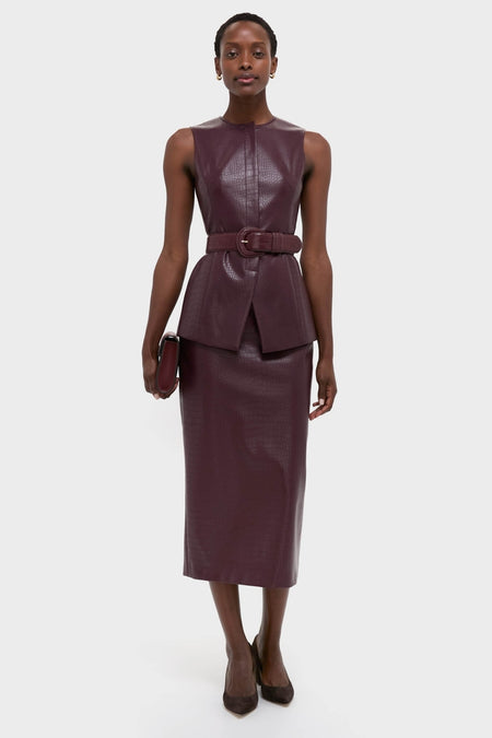 Model in classic Plum Stamped Faux Leather Ellington Skirt and top, exuding effortless high-end style with a fun, coordinated burgundy faux-leather ensemble and chic clutch.