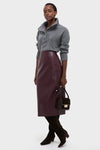 Model showcasing the Plum Stamped Faux Leather Ellington Skirt, a classic, high-end midi with a croc-embossed texture, styled effortlessly with a chunky knit sweater.