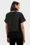 Back view of a woman wearing the Black Dupioni Chadwick Tassel Top, showcasing its classic, effortless silhouette and high-end macramé fringe hem detail, perfect for any fun occasion.