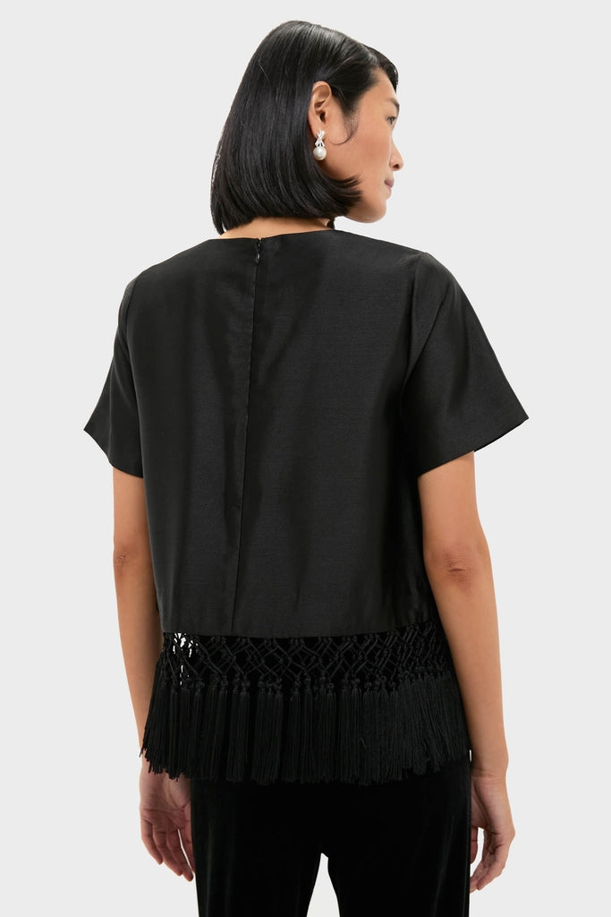 Back view of a woman wearing the Black Dupioni Chadwick Tassel Top, showcasing its classic, effortless silhouette and high-end macramé fringe hem detail, perfect for any fun occasion.