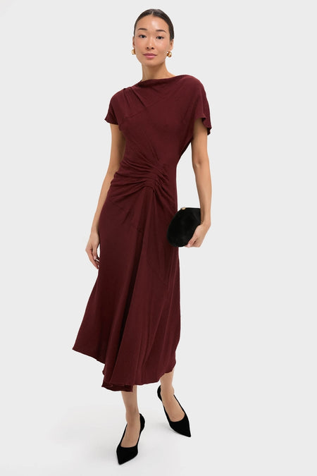 Model in classic Black Cherry Dena Midi Dress with ruched waist, draped neckline, asymmetrical hem; paired with black heels and clutch, exuding effortless, high-end style.