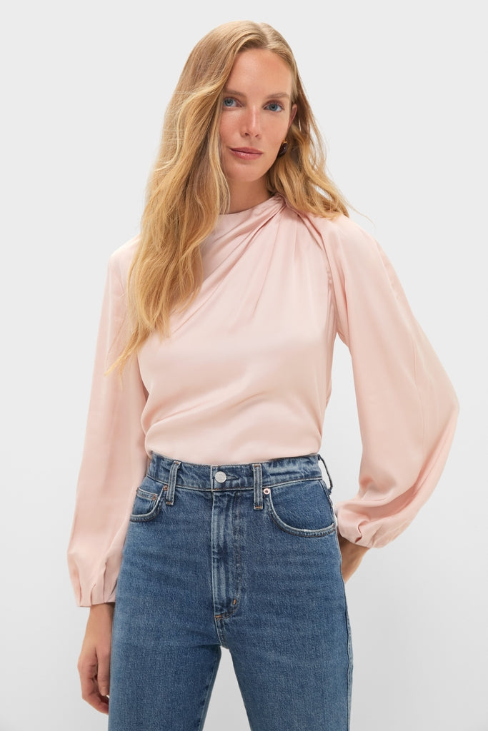 Woman modeling Soft Pink Blush Satin Blaire Top with gathered shoulders and blouson sleeves, paired with classic high-waisted blue jeans, for an effortless, high-end look.