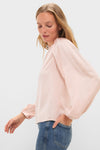Model in profile wears the classic Soft Pink Blush Satin Blaire Top with effortless blouson sleeves and gathered shoulders, paired with medium-wash jeans for a fun, high-end look.