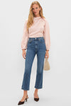 Woman in a classic, high-end Soft Pink Blush Satin Blaire Top with blouson sleeves, paired with effortless blue jeans and fun brown slingback heels, holding a gold clutch.