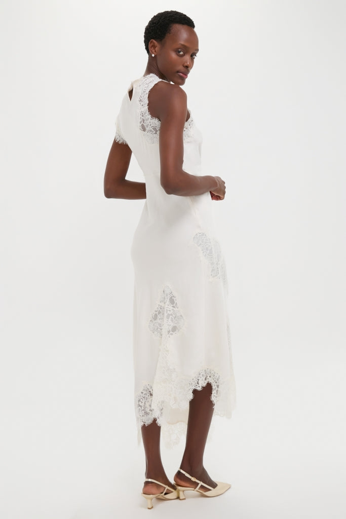 Woman in a classic, high-end Creme Satin Lace Alessia Midi Dress with lace panels, paired with effortless, fun, pointy-toe slingback shoes.