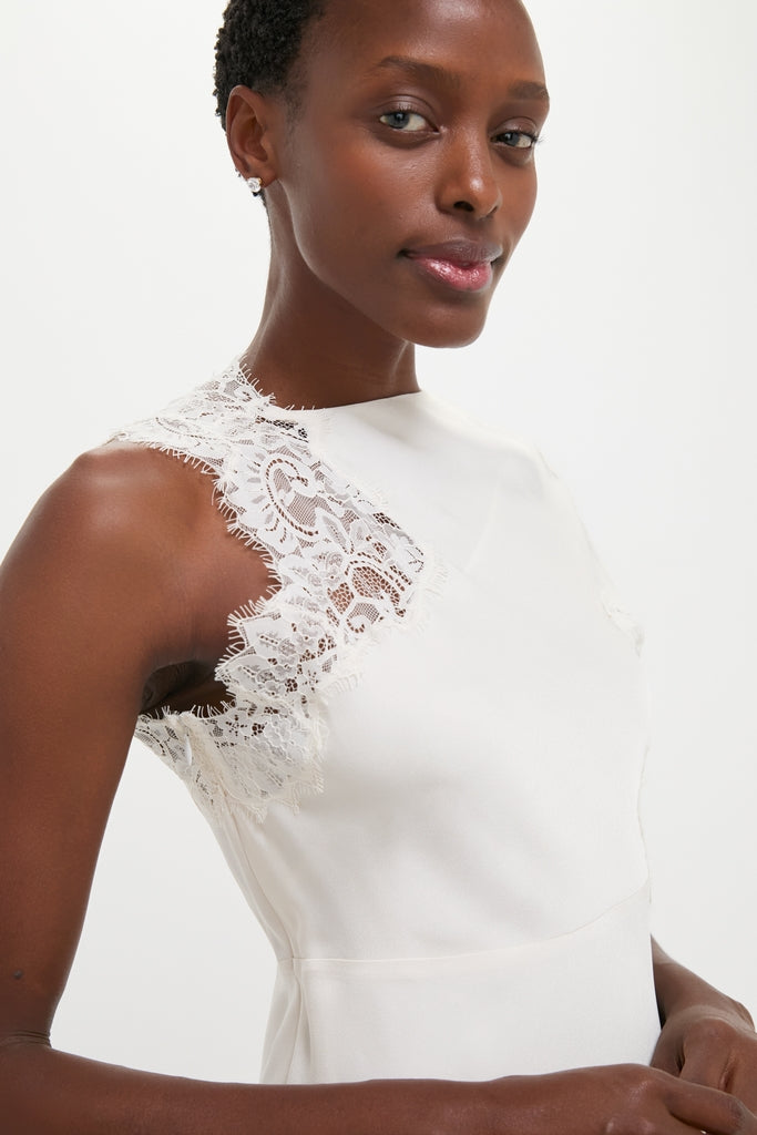 Close-up of a person in a classic, effortless Creme Satin Lace Alessia Midi Dress by A.L.C., showcasing high-end lace detailing for a fun, sophisticated look.