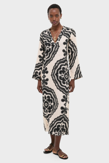 Model in Niku Cream Theodora Column Dress with bell sleeves, epitomizing classic elegance and effortless style, complemented by gold jewelry and black sandals for a high-end, fun look.