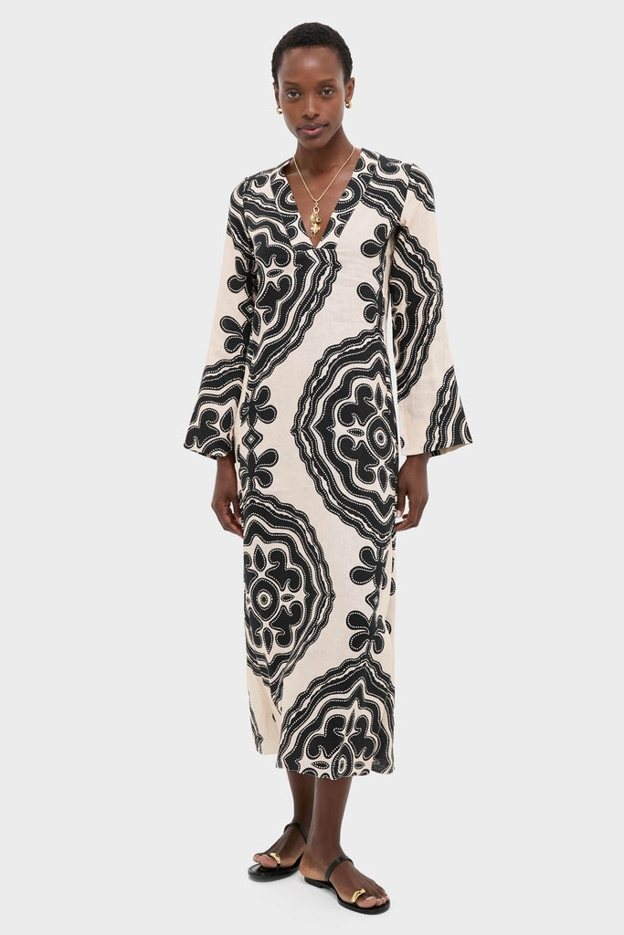 Model in Niku Cream Theodora Column Dress with bell sleeves, epitomizing classic elegance and effortless style, complemented by gold jewelry and black sandals for a high-end, fun look.