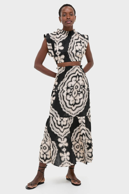 Woman models the classic Niku Black Sanaa Skirt, showcasing its effortless elegance with a bold graphic print, adjustable tie belt, and button-front, embodying high-end, fun style.