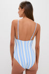 Rear view of a woman in the classic Debre Sky Elene One Piece, featuring light blue and white stripes, adjustable straps, and a scooped back, embodying effortless high-end style.