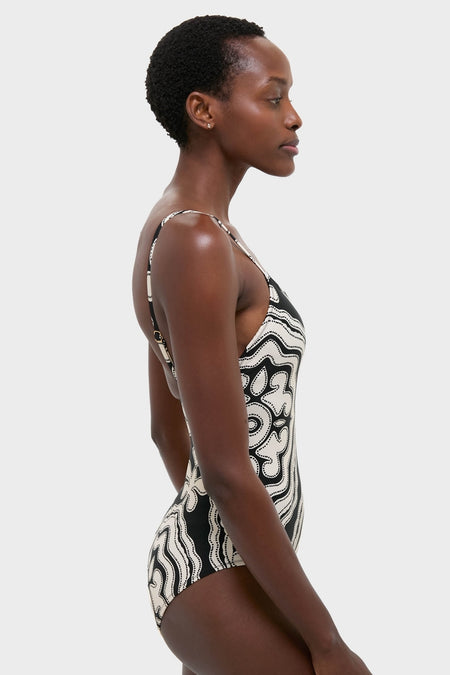 Woman wearing Niku Black Elene One Piece swimsuit, showcasing a classic, effortless design with thin adjustable straps, abstract pattern, and high-end details for a fun, confident style.