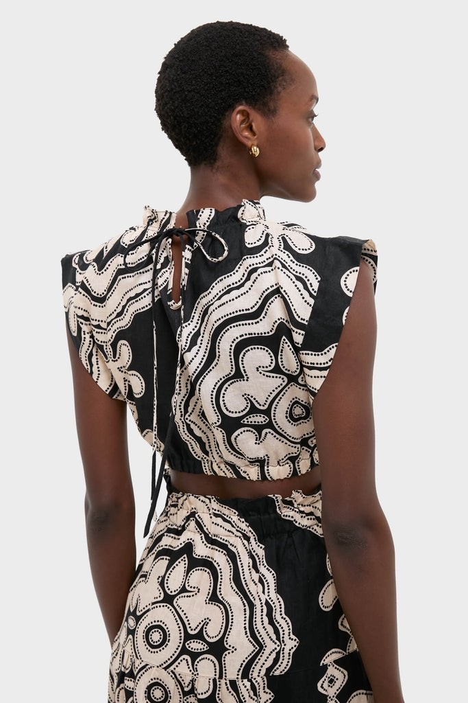 Woman in Niku Black Muna Ruched Crop Top with abstract dot print, featuring a ruched neckline and back tie, embodying classic, effortless style.