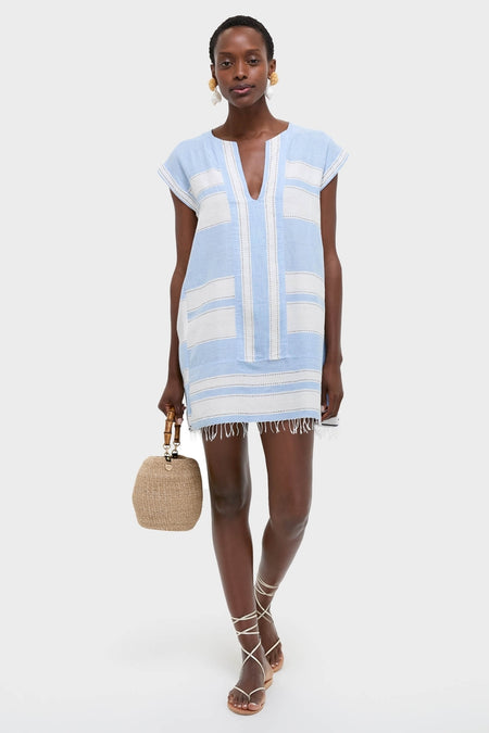 Model in Debre Sky Elina Caftan, a classic, effortless mini dress with white panels, paired with a fun straw handbag and high-end strappy sandals.