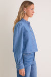Model wearing Indigo Denim Margot Top, a classic, effortlessly stylish chambray blouse with blouson sleeves and silver buttons, embodying high-end, fun fashion.