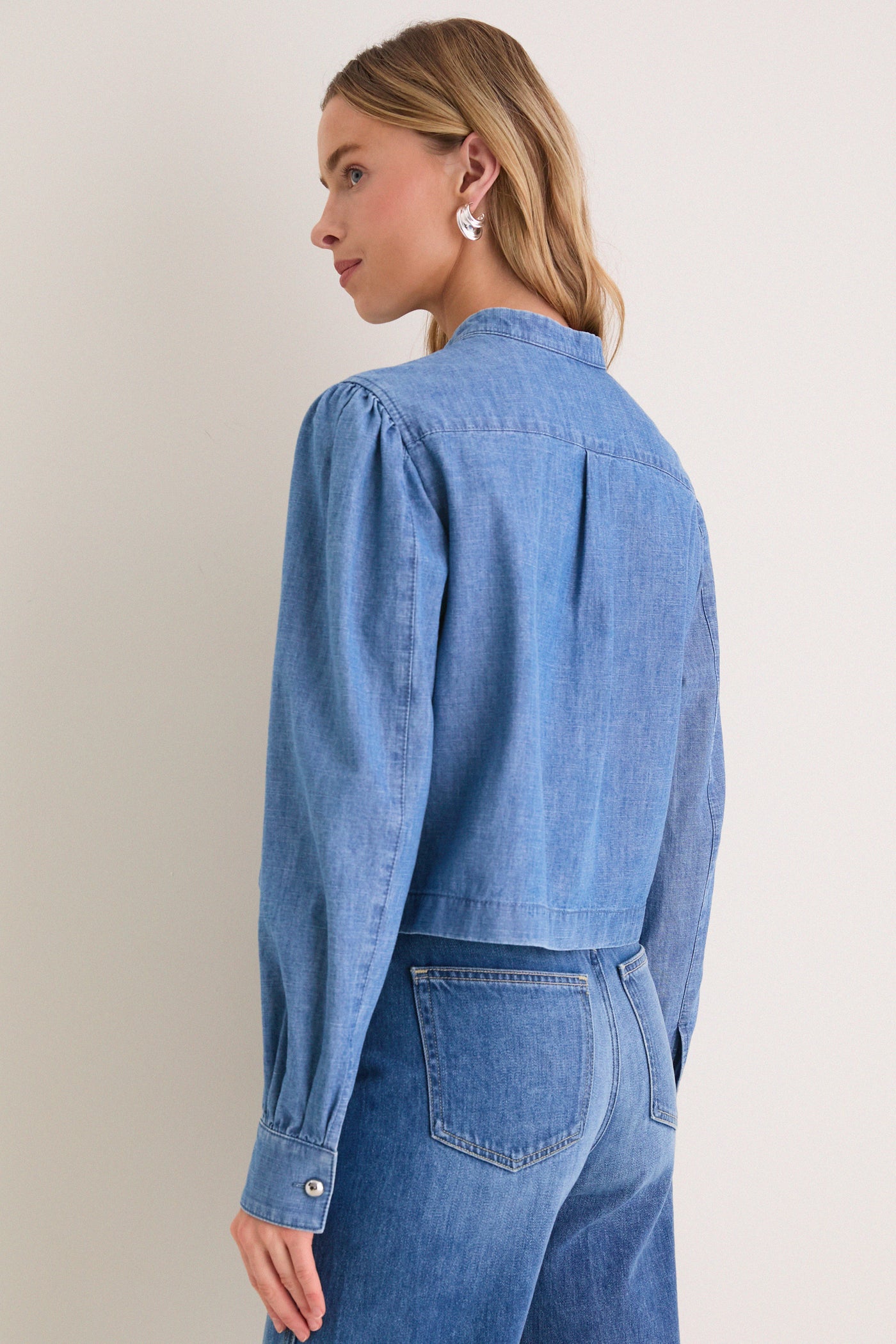 Person in classic Indigo Denim Margot Top with rounded collar and subtle balloon sleeves, embodying effortless, high-end style. Perfect for fun, confident outings.